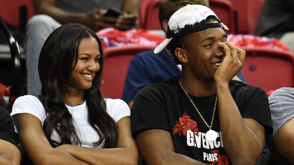 Deja Lighty, laughing, in the stands, white shirt, armed folded; Donovan Mitchell, laughing, in the stands, hands on his face