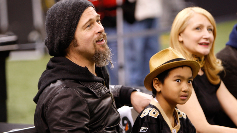 Brad Pitt sits on the sideline with Maddox in a Saints jersey