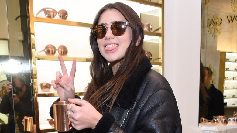 Dua Lipa smiling and throwing up a peace sign