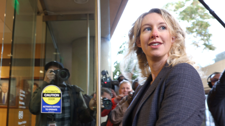 Elizabeth Holmes smiling at photographers while walking through door