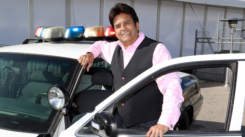 Erik Estrada posing with a Police Chase Las Vegas police car