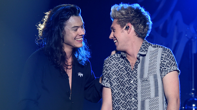 Harry Styles and Niall Horan smiling at each other onstage