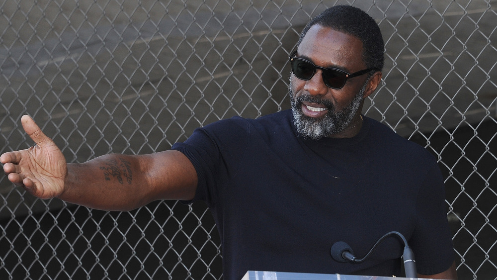 Idris Elba holding his arm out