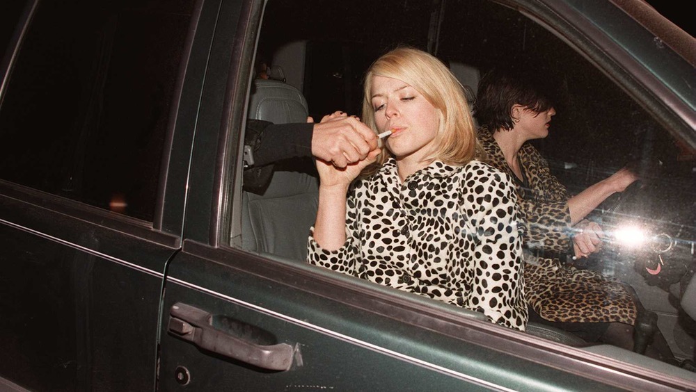 A man lights Amanda de Cadenet's cigarette 