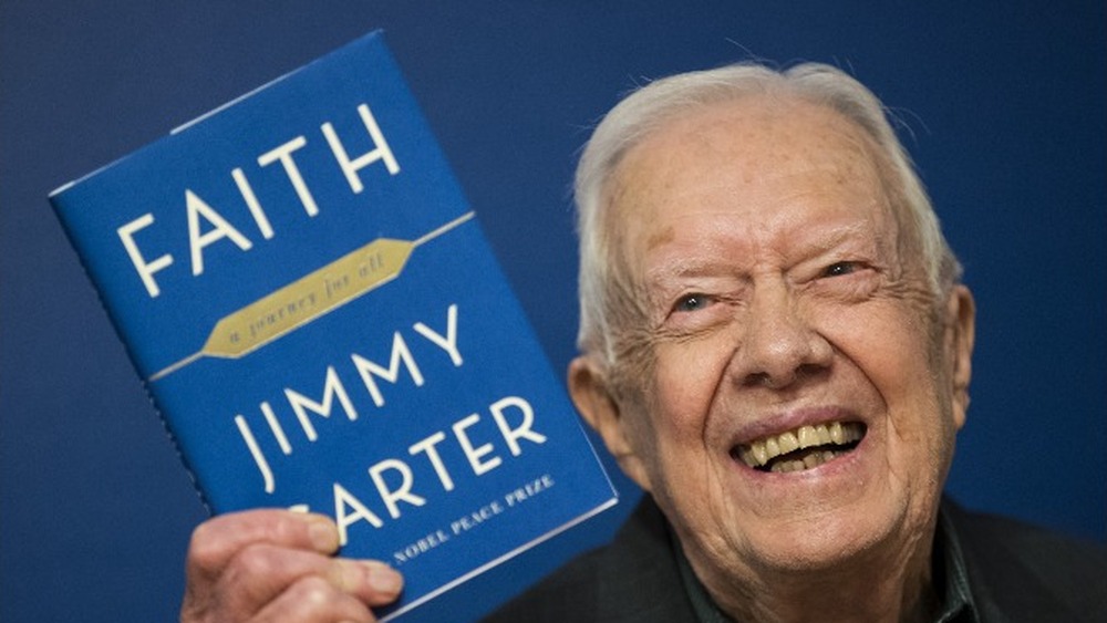 Former U.S. President Jimmy Carter holds up a copy  'Faith: A Journey For All' at a book signing event in 2018