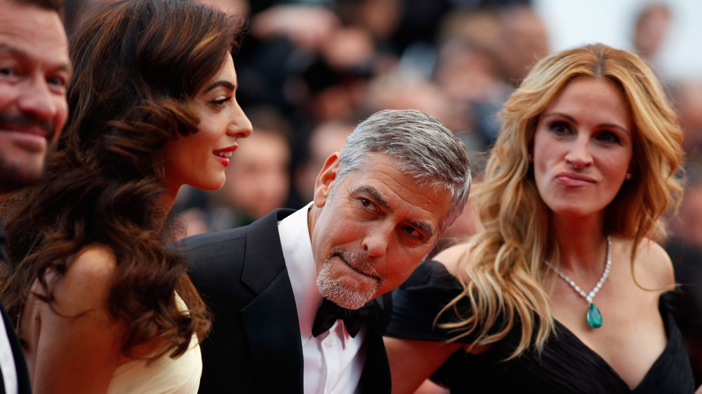 Amal Clooney, George Clooney, and Julia Roberts posing on the red carpet