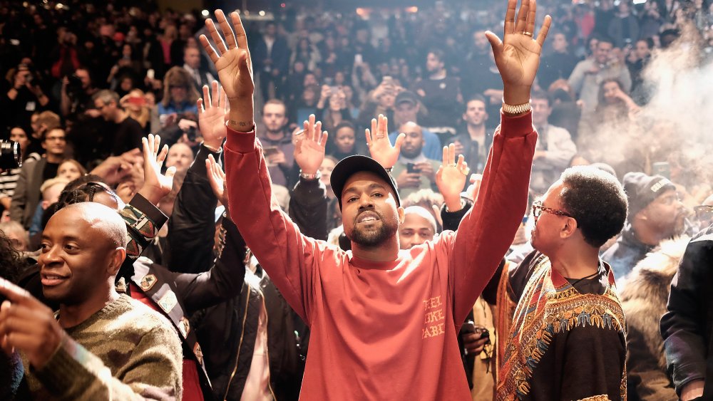 Kanye West at a show, hands raised