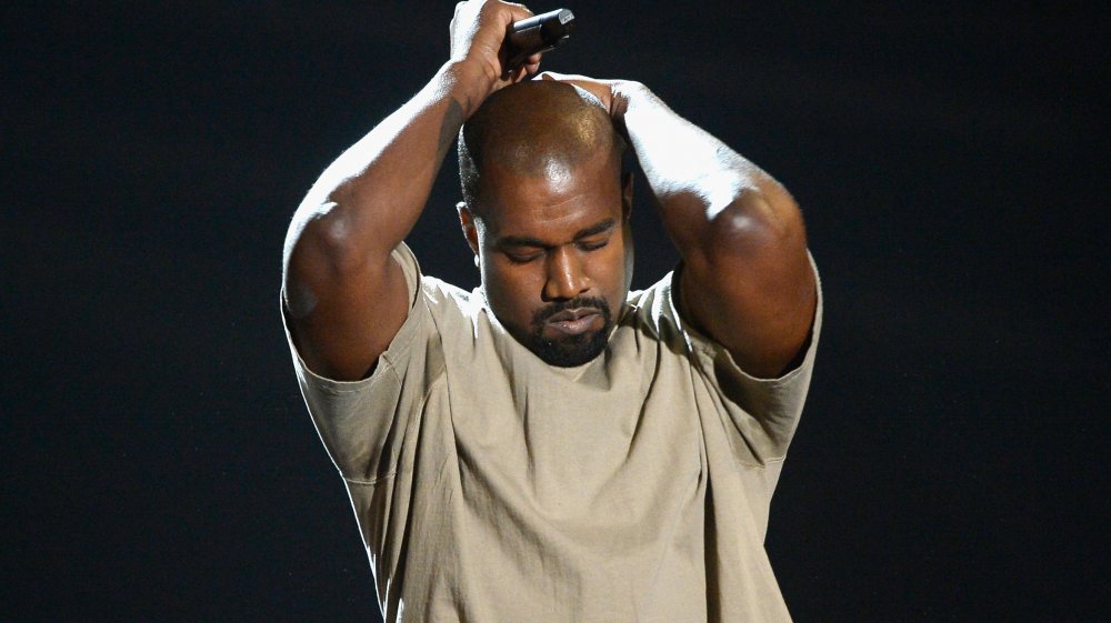 Kanye West with hands over head, performing