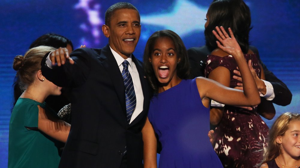 Barack Obama and Malia Obama, smiling while arm in arm, at a political event