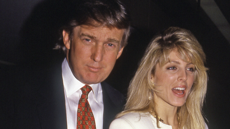 Donald Trump looks at camera with Marla Maples talking to someone off camera 