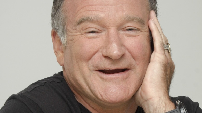 Robin Williams smiling with hand to his face