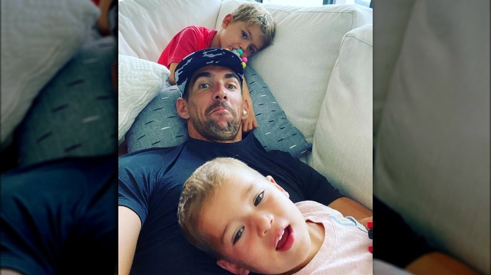 Michael Phelps and his sons posing for a selfie on the couch