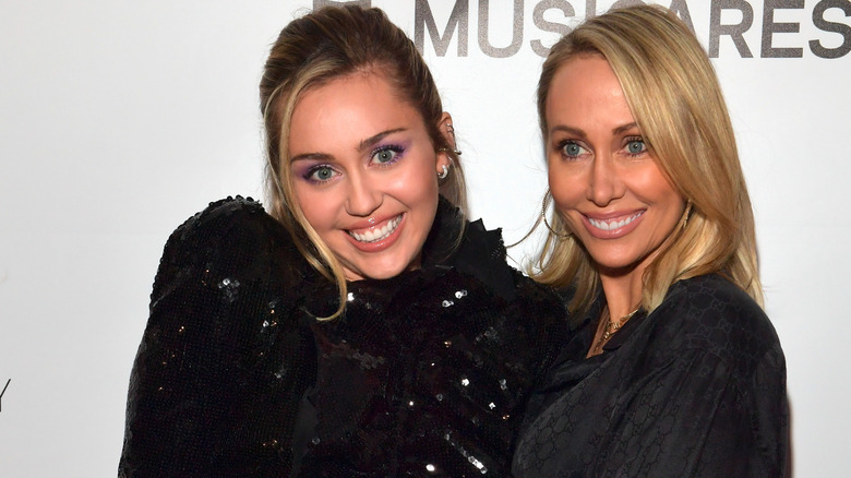 Miley and Tish Cyrus stand together smiling