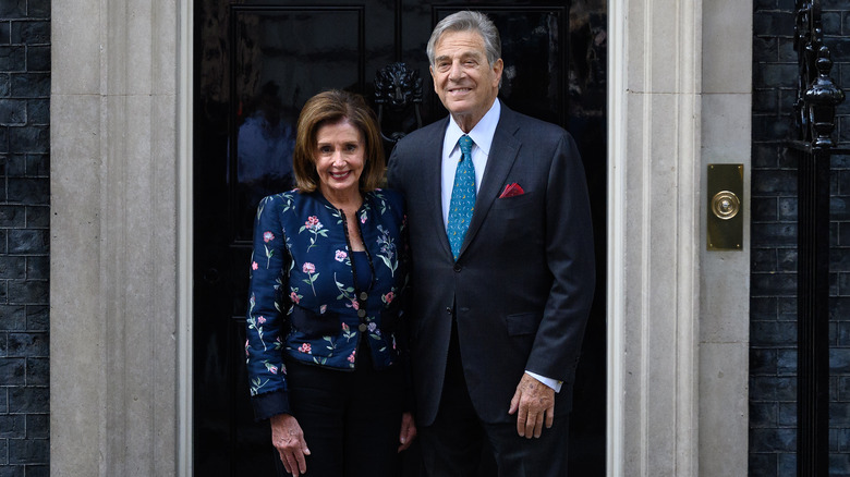 Nancy and Paul Pelosi smiling in front of a door