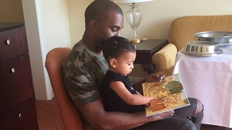 Kanye West reading book with North West