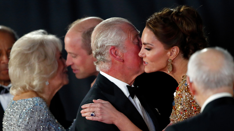 Camilla, Duchess of Cornwall kisses Prince William, Duke of Cambridge and Prince Charles, Prince of Wales kisses Catherine, Duchess of Cambridge as they arrive to attend the "No Time To Die" World Premiere