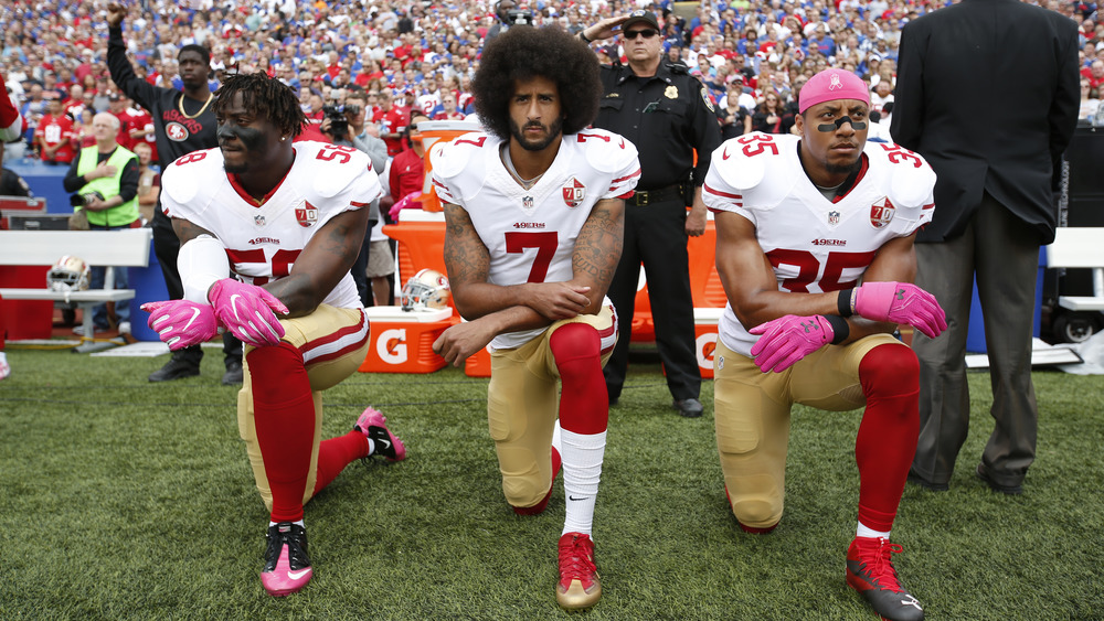 Eli Harold, Colin Kaepernick, and Eric Reid kneeling in protest