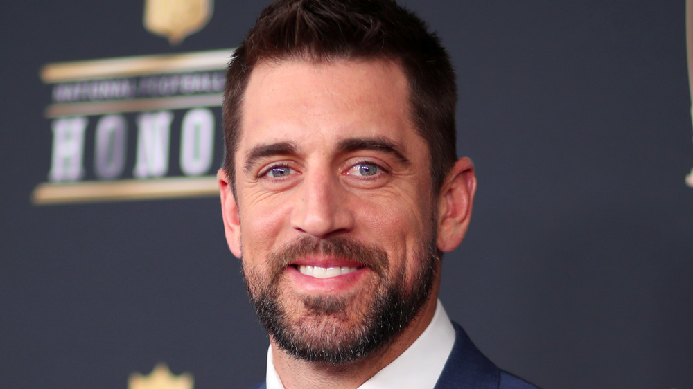 Aaron Rodgers smiles in a suit.