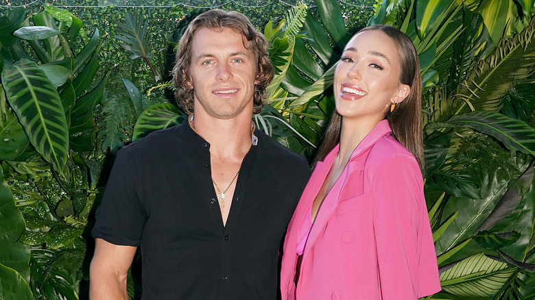 Braxton Berrios wears a black dress shirt, and Sophia Culpo wears a pink outfit 