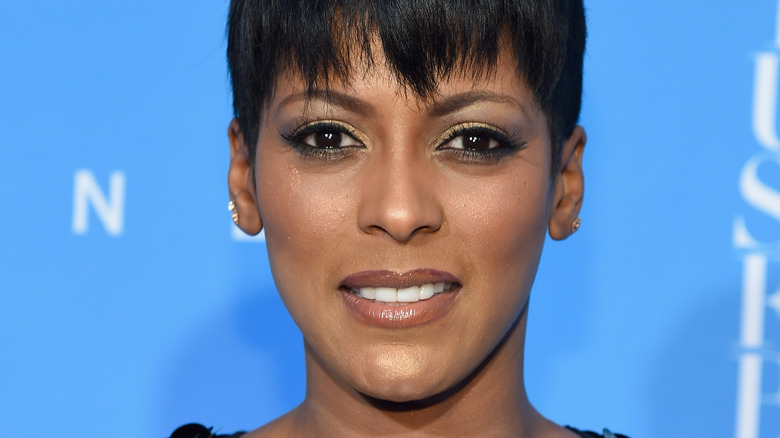 Tamron Hall in front of a blue wall, smiling