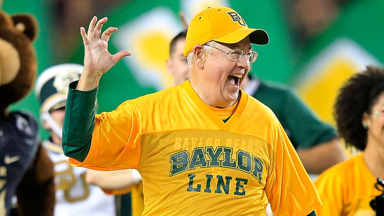 Ken Starr smiling while holding up his hand 