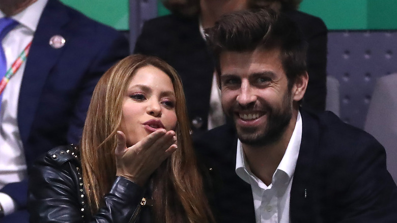 Shakira blowing a kiss and Gerard Piqué laughing