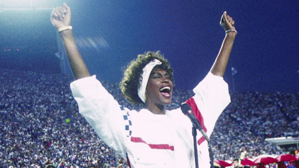 Whitney Houston with hands up, singing