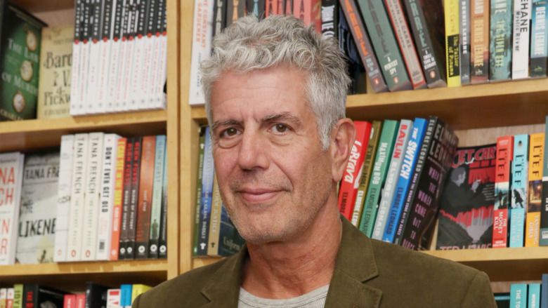 Anthony Bourdain in front of a bookshelf