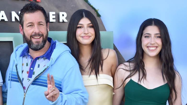 Sadie and Sunny posing with dad Adam Sandler on red carpet