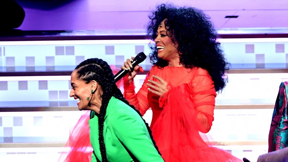 Tracee Ellis Ross in a green suit, Diana Ross in a red dress, both laughing on stage at the 2019 Grammys