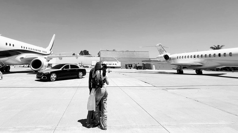 Kylie Jenner and Travis Scott standing in front of private jets