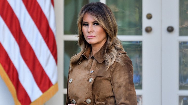 Melania Trump standing outside the White House with serious expression