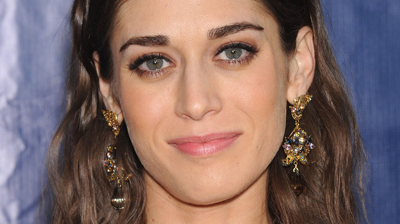 Lizzy Caplan poses in intricate gold earrings