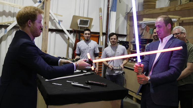 Prince Harry and Prince William sparring with lightsaber swords