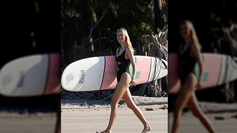 Ivanka Trump walking on the beach holding a surfboard