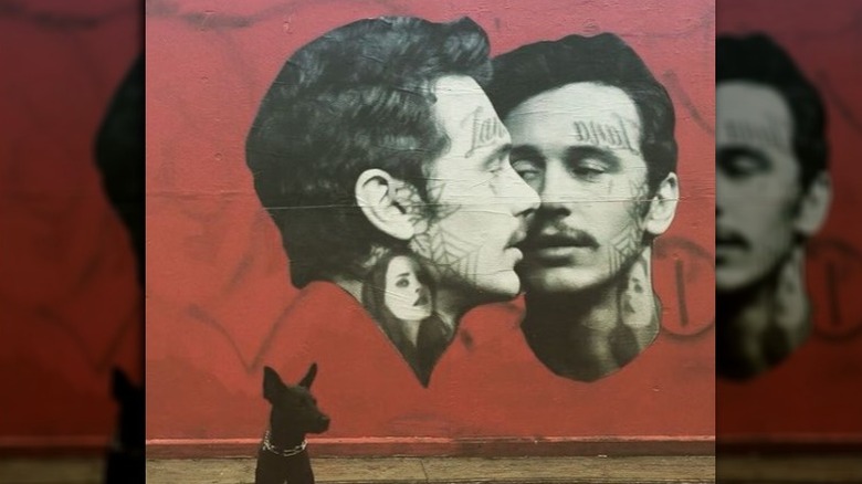 Artist Cheyenne Randall's dog in front of his mural art of James Franco