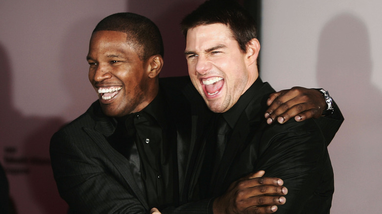 Jamie Foxx laughing and hugging Tom Cruise