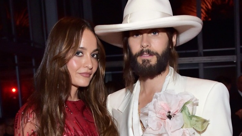 Jared Leto in hat beside Chloe Bartoli