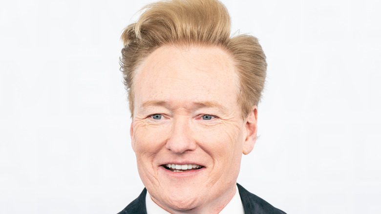 Conan O'Brien stands in front of a white background