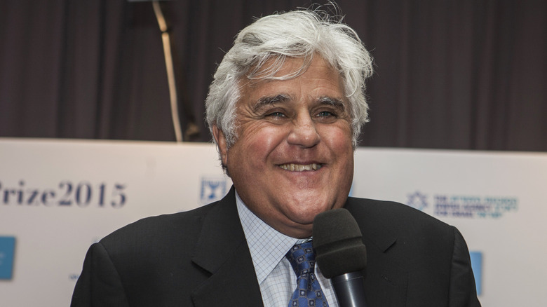 Jay Leno smiling with teeth and holding microphone