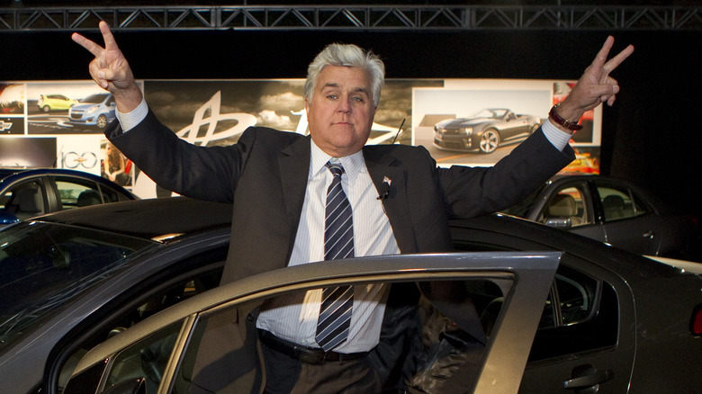 Jay Leno giving peace signs near a car