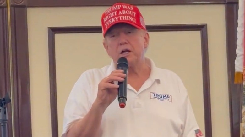 Donald Trump giving a speech while wearing a hat that says "Trump was right about everything"