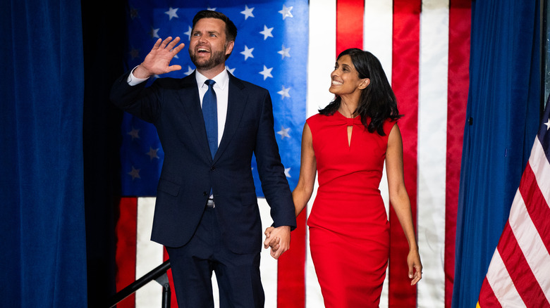 JD and Usha Vance holding hands and smiling on stage