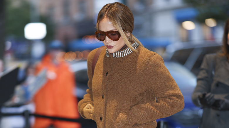 Jennifer Lopez wearing glasses and a brown jacket