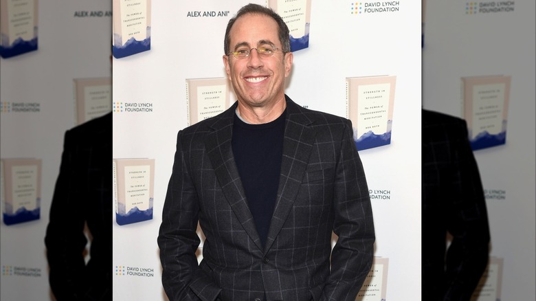 Jerry Seinfeld smiling in a checked jacket