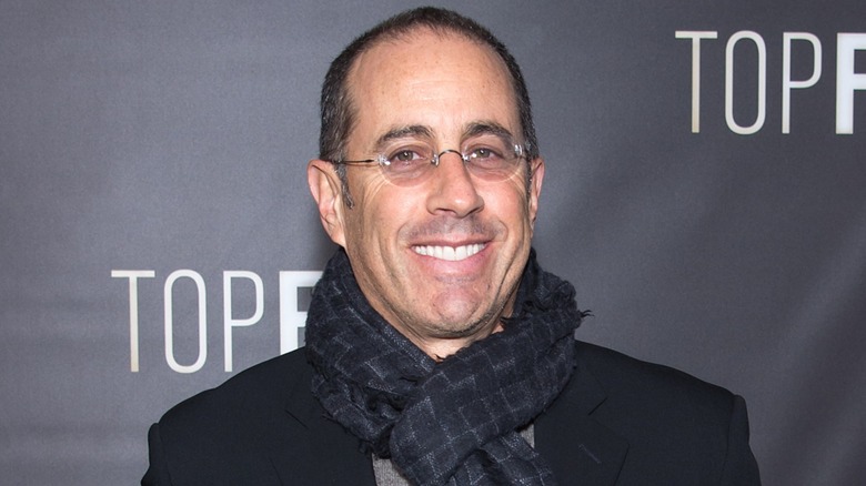 Jerry Seinfeld smiling, wearing a checked scarf