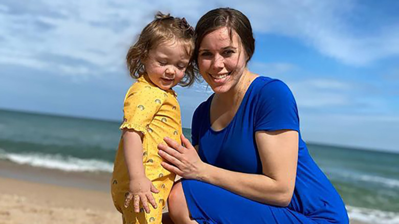 Jessa Seewald holding son at the beach wearing swim dress