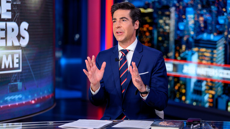 Jesse Watters at a tv desk speaking with hands raised