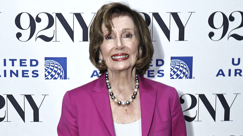 Nancy Pelosi wearing pearl necklace and fuchsia coat on the red carpet