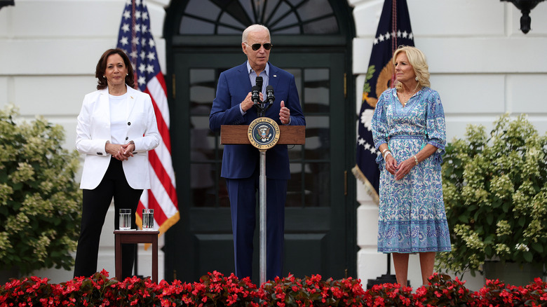 Kamala Harris and Jill Biden standing next to Joe Biden speaking